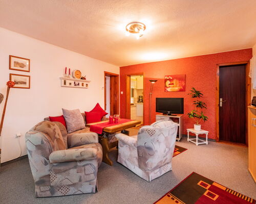 Innenaufnahme Zimmer mit Sofa, Sesseln, TV und Tisch