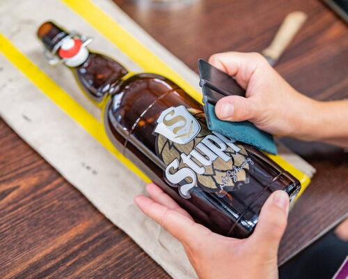 Beklebung einer abgefüllten Flasche Stupps Bier mit Logo